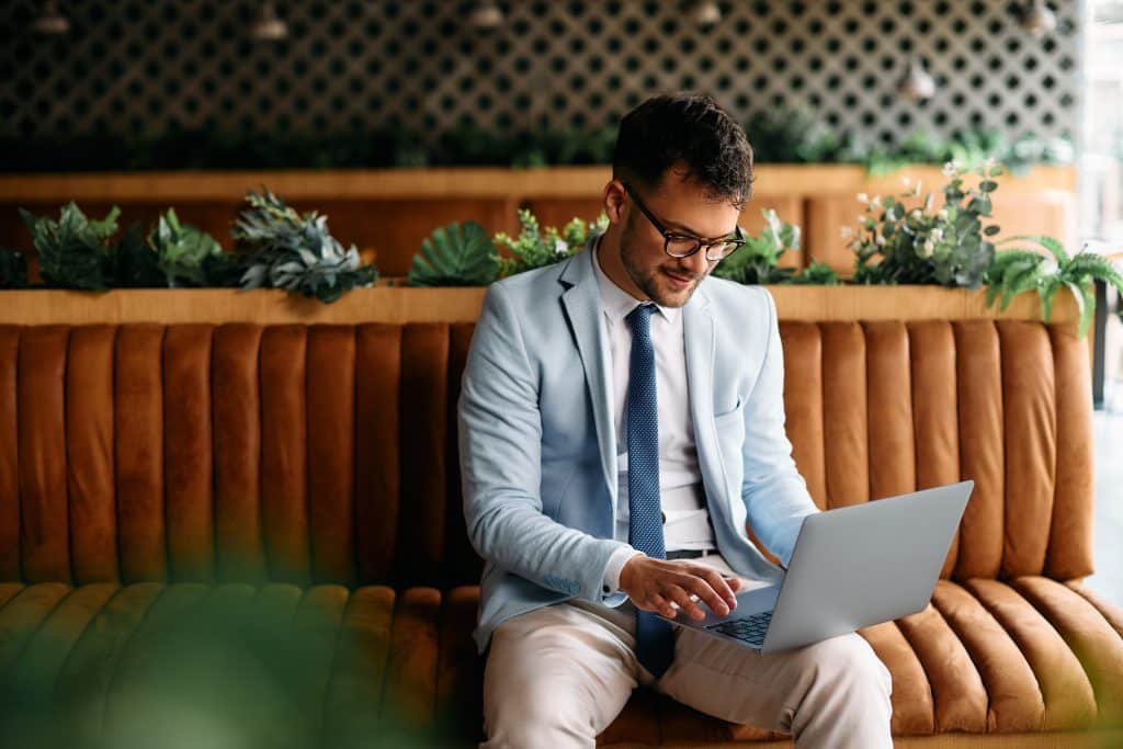 A man sitting on a couch using a laptop.