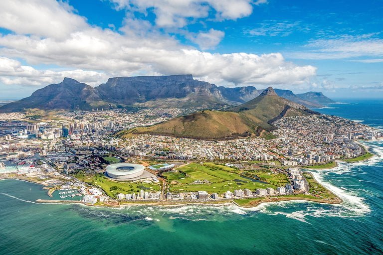 Aerial view of cape town with table mountain in the background and the cape town stadium in the foreground.